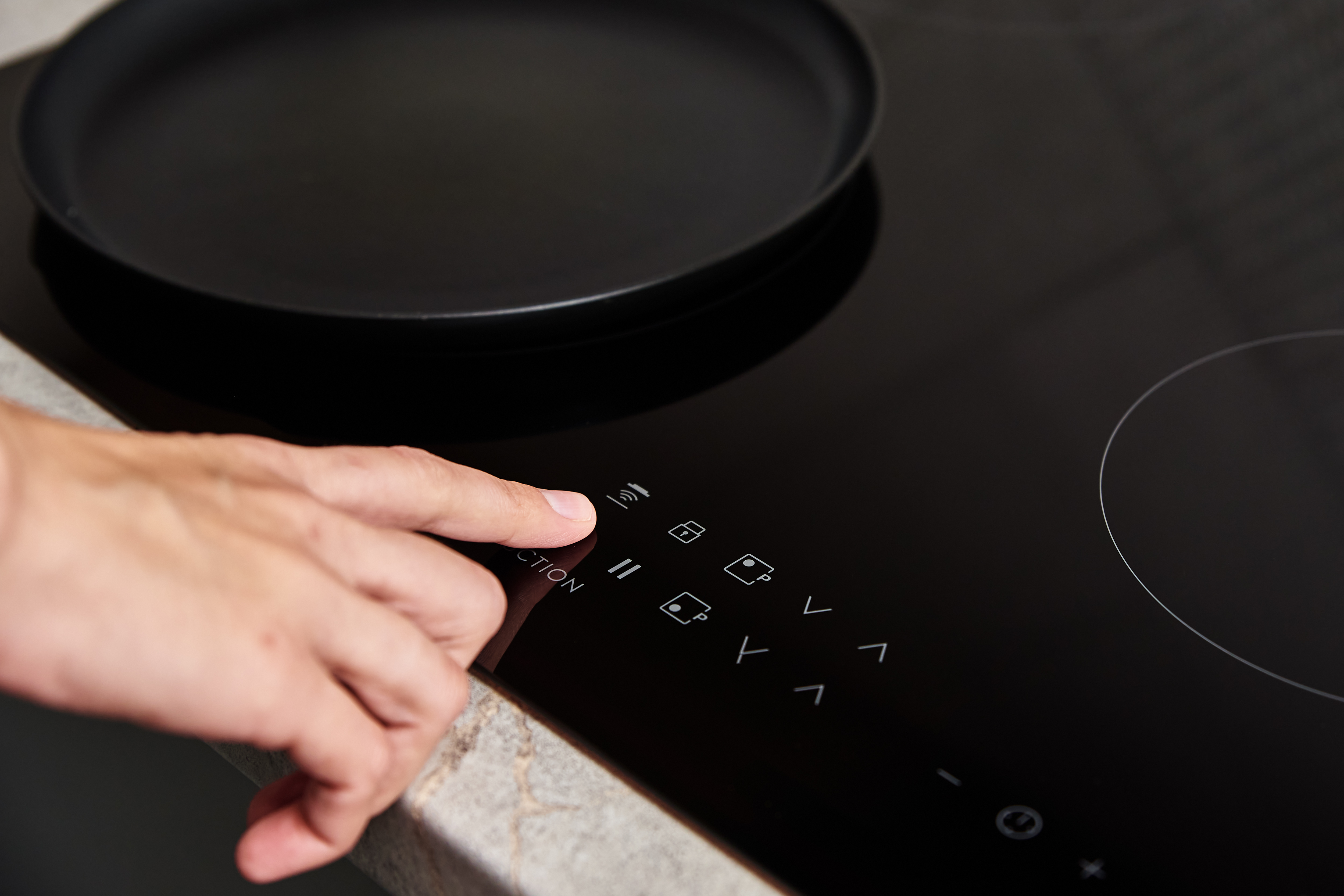 Woman hand turns on modern induction stove in the kitchen